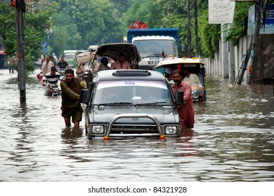 LAHORE, PAKISTAN, SEPT 08: Motorists push their closed vehicle while they are passing through a flooded road during heavy downpour of Monsoon season in Lahore on Thursday, September 08, 2011.