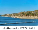 Lake Austin, Austin, Texas- Docks at the front of the rich neighborhood on top of the slope. There are large residential buildings on top with docks near the shore.