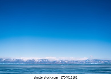 Lake Baikal in March. Winter Baikal. Beautiful winter landscape with a smooth surface of blue ice with lines of cracks. - Shutterstock ID 1704015181