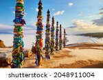 Lake Baikal, Olkhon Island in winter. Wooden ritual pillars with colorful ribbons on cape Burhan or Shamanka rock. 