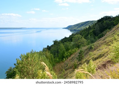 a lake with blue water and the hill with green trees copy space  - Powered by Shutterstock