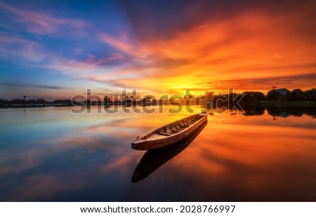 Lake boat at orange sunset. Scenic sunrise background