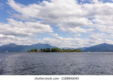 Lake Chiemsee, Bavaria, Germany - 10th June 2022: A german photographer visiting a lake in the bavarian alps during summer time. View from the shorefront across the lake to the alps.