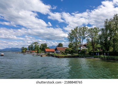 Lake Chiemsee, Bavaria, Germany - 10th June 2022: A german photographer visiting a lake in the bavarian alps during summer time. View from the shorefront across the lake to the alps.