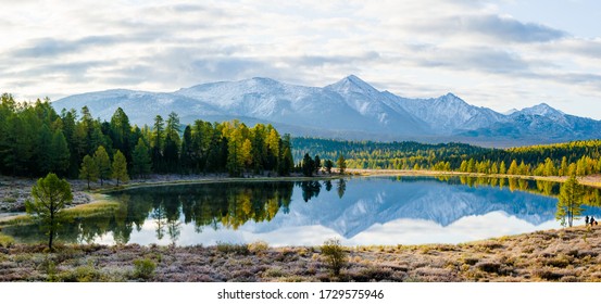 Озеро Веселый Алтай, Сибирь, пасмурный осенний день. Тайга, красивое небо, дымка, горы со снежными вершинами, панорама.