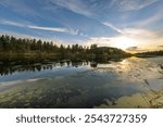 A lake with a cloudy sky in the background. The sky is blue with a few clouds. The lake is calm and peaceful