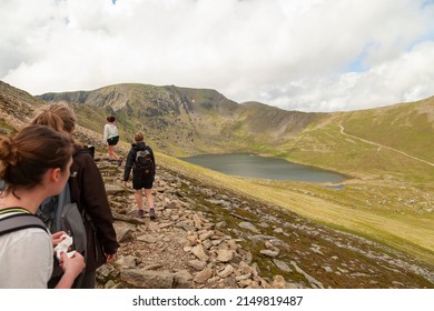 Lake District, England - May 26, 2014: A group of young women walk on a hike to the Helvellyn Edge as they look down on the small Red Tarn Lake, county of Cumbria, UK