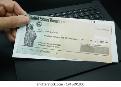 Lake Elsinore, CA USA - March 29, 2021:  A Mans Hand Holding A US Treasury Illustrative Check To Illustrate American Rescue Plan Act Of 2021 Payment Over A Computer Keyboard.