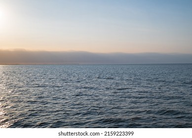 Lake Erie with shoreline in the distance with the early evening setting sun. It is the fourth largest lake of the five Great Lakes in North America. At its deepest point it is 210 feet deep.