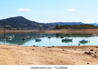 Lake With Extremely Low Water Level Has Several Yachts Moored. All Have Perfect Reflections In The Still Water