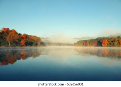 Lake fog with Autumn foliage and mountains with reflection in New England Stowe