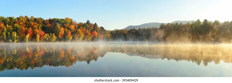 Lake fog panorama with Autumn foliage and mountains with reflection in New England Stowe