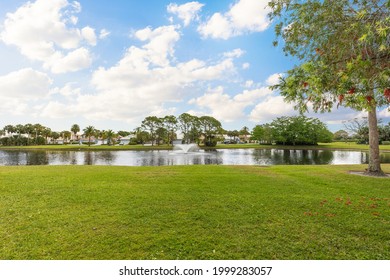 Lake with fountains in the middle of a residential complex in Miami. Trees, grass and a blue sky.