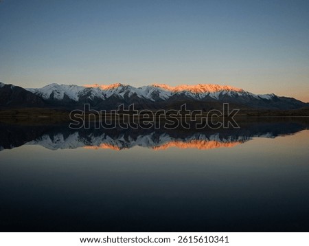 Lake Heron idyllic remote rural countryside golden hour orange moutain peaks alpenglow winter sunset, Southern Alps landscape at Ashburton Lakes Canterbury South Island New Zealand