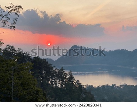 the lake and hills above Gunung Wilis in the afternoon with an orange sunset. the sun has set. mountain. lake.