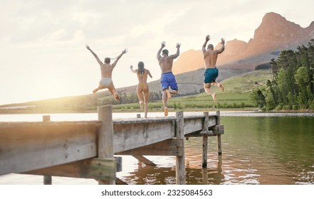 Lake, jump and group of friends for holiday, summer camping and freedom, celebration or success from behind. carefree, cheers and excited people in air for swimming, water and mountains on vacation - Powered by Shutterstock