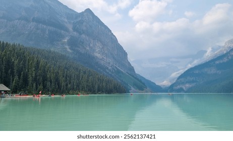 Lake Louise, Alberta, Canada - August 8 2023: Red canoe floating in turquoise water at Lake Louise. Couple canoeing together in the beautiful glacial Lake Louise at sunrise - Powered by Shutterstock