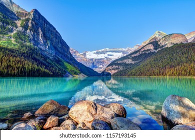 Lake Louise in Banff National Park with its glacier-fed turquoise lakes and Mount Victoria Glacier in the background. Visitors paddling red canoes in the distance. - Shutterstock ID 1157193145