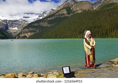 LAKE LOUISE, CANADA - JULY 8, 2018: Representative Of Nakoda Cree, First Nations Elder On The Shores Of Lake Louise In Banff National Park, Alberta. Banff National Park Is UNESCO World Heritage Site