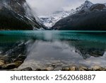 Lake Louise during early morning in Autumn with fog coming down the snowy mountains and glacier with their reflection on the blue turquoise water in Banff National Park