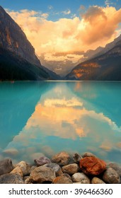 Lake Louise at sunrise with rocks in Banff national park with mountains and forest in Canada.