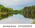 Lake in Nipigon Ontario Canada showing scenic view of Cedar Pine forest, island, mirror reflection under overcast sky in summer