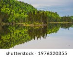Lake in Nipigon Ontario Canada showing scenic view of Cedar Pine forest, island, mirror reflection under overcast sky in summer