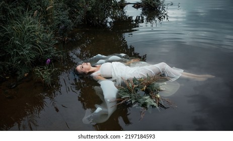 A Lake Nymph In A White Dress And A Wreath Of Flowers Floats On The Surface Of The Water. A Young Woman In A Folk Image, A Mystical Story