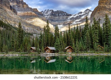 Lake O'Hara cabins reflecting in the emerald water of the lake with mountain peaks in the background, Yoho National Park, Canada. - Shutterstock ID 2108612231