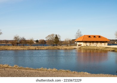 A Lake And An Old Stone Building Against A Blue Sky.