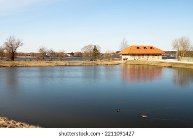 A Lake And An Old Stone Building Against A Blue Sky.