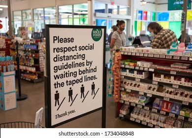 Lake Oswego, OR, USA - May 15, 2020: The Sign At The Checkout Lane In A Whole Foods Market Reminds Shoppers To Respect Social Distancing Guidelines By Waiting Behind The Taped Lines On The Floor.