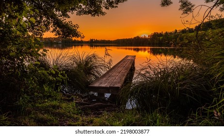 Lake pier in the early morning at dawn. Lakeview at dawn in early morning. Early morning sunrise over forest lake. Lake per at dawn