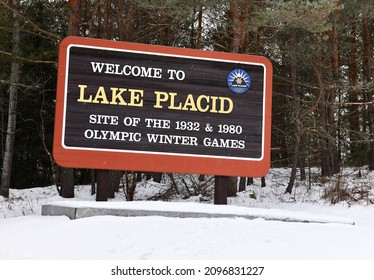 LAKE PLACID NEW YORK DECEMBER 2021. Lake Placid Village Sign Along Road In The Adirondack Mountains In Snow Depicting The Home Of The Winter Olympics In 1932 And 1980