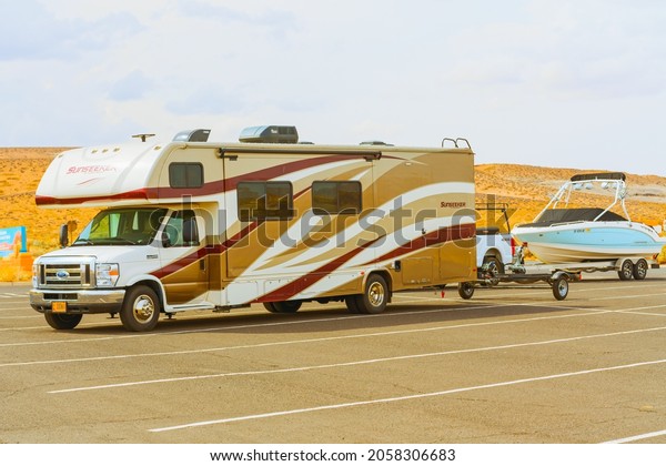 Lake Powell, Utah,\
USA - September 29, 2021 Travel trailer towing a boat. Lake Powell\
beach, parking lot