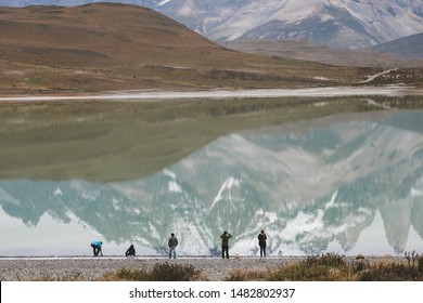 Lake with reflection of a snowed mountain and some people standing on the shore