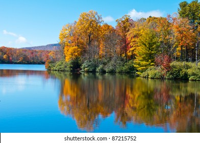 Lake reflections of fall foliage. Colorful autumn foliage casts its reflection on the calm waters of a North Carolina lake along the Blue Ridge Parkway. - Powered by Shutterstock
