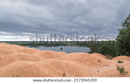 A lake with a sandy mountain. Like on Mars. An unusual lake shore. Stormy sky. Martian species