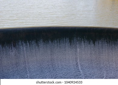 Lake Spillway-foaming Water Over Curved Surface As It Runs Over The Edge