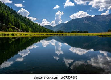 Lake in the summer alps reflecting the sky with clouds.
