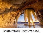 Lake Superior Ice Cave at Sunrise. The sun crests the horizon and shines through hanging ice curtains as it rises and illuminates the interior of a cave on Grand Island in Michigans Upper Peninsula.