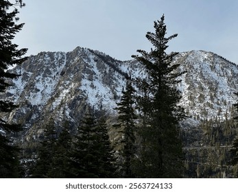 Lake Tahoe in late December with light snow, calm water, and snowy peaks in the distance.