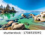 Lake Tahoe rocky shoreline in sunny day, beach with blue sky over clear transparent water