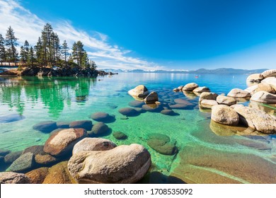 Lake Tahoe rocky shoreline in sunny day, beach with blue sky over clear transparent water