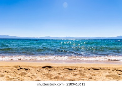 Lake Tahoe sandy beach view in summer with tropical blue waters, blue sky and footprints in sand. - Powered by Shutterstock