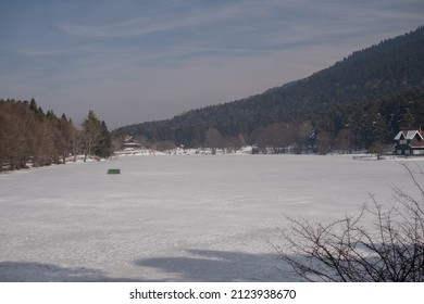 Lake View House, Frozen Lake. House With Forest Behind. Snowy Weather.