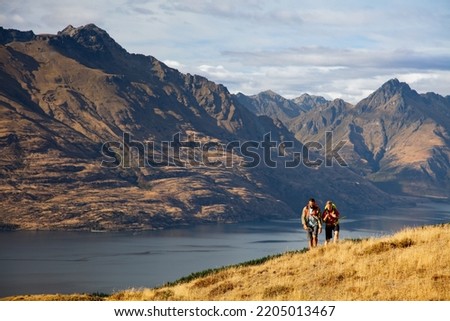 Lake Wakatipu Queenstown fit extreme Caucasian male and female young hiking couple walking mountain travel trail outdoors The Remarkables Otago New Zealand