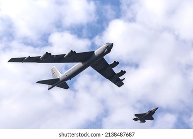 LAKENHEATH, SUFFOLK, UK - MARCH 22, 2022: A rare sighting, Boeing B-52 Stratofortress AF61-018 MT, 23d Bomb Squadron, MINOT AFB carries out a low pass over RAF Lakenheath, escorted by a pair of F-35's