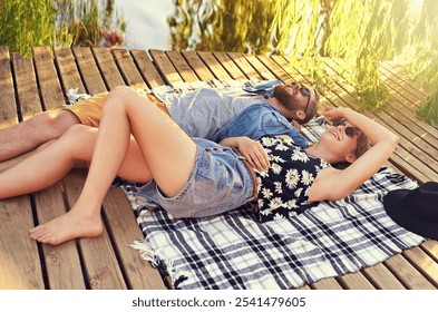 Lakeside, couple and happy with lying on ground on break with love, rest and affection for care. Date, outdoor and smile in relationship on blanket on valentines day for holiday to relax and bonding - Powered by Shutterstock