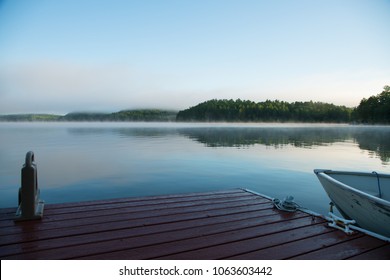 A lakeside dock and fishing boat on an Ontario lake in the morning mist